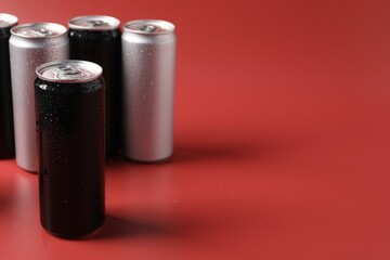 Many aluminium cans of beverage on red background, space for text