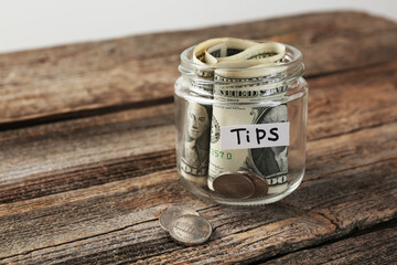 Glass jar with tips on wooden table, closeup. Space for text
