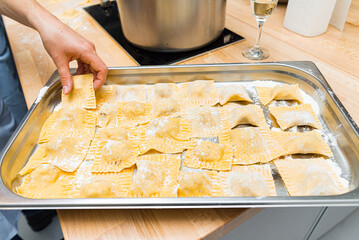 Fresh homemade ravioli on floured tray. A tray of freshly made ravioli dusted with flour, ready for...