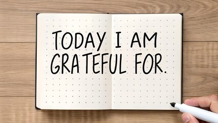 Journaling gratitude concept with a person writing Today I Am Grateful For, on a dotted notebook, emphasizing positivity, self-care and mental wellness