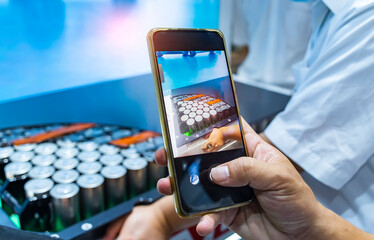 man use mobile phone taking photos of metal parts with shiny steel cylindrical surface closeup....