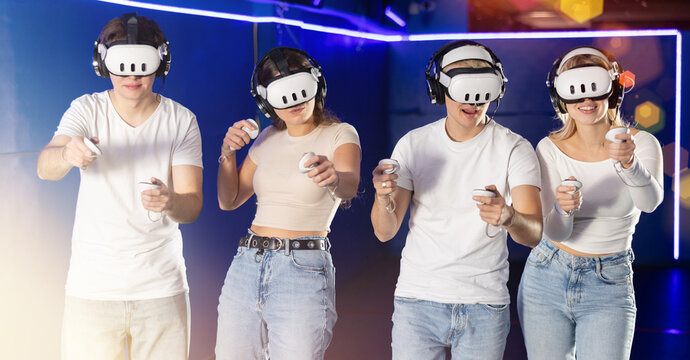 Guys and girls friends experiences effect of being immersed in fictional reality with help of helmet. Gamer manipulate joystick and plays virtual game with companions. E sports competition, new