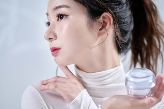 A beautiful female model holds cosmetics and poses in various ways in front of a tree shadow background