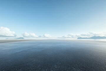Empty asphalt road leads to distant mountains under a clear sky.