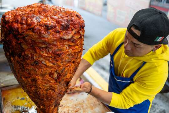 Street vendor preparing tacos al pastor at a traditional mexican taqueria