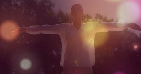 Practicing meditation outdoors, woman with arms outstretched embracing peaceful energy