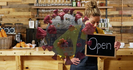 Cafe worker holding Open sign, preparing for customers during pandemic