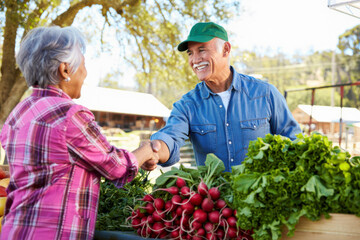 Happy Farmer and Senior Woman Shaking Hands at Farmers Market