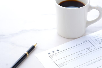 就職活動（就活）のために、コーヒーを飲みながら、履歴書を作成する
