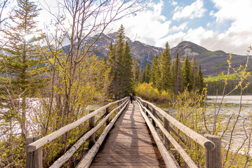 Incredible nature views at Pyramid Lake in Jasper National Park during spring time with woman tourist, standing on iconic, popular bridge area of Canada in Canadian Rockies