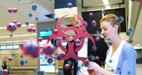 People at airport checking phone with virus particles and biohazard symbol overlay