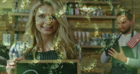 Fototapeta premium Barista preparing coffee while smiling woman holding chalkboard in cafe