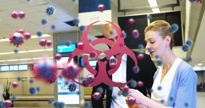 People at airport checking phone with virus particles and biohazard symbol overlay