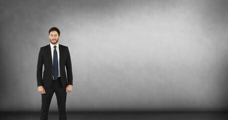 Businessman in formal suit standing confidently, smiling against gray background