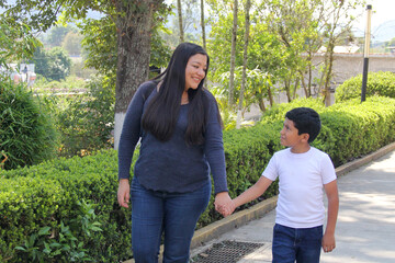A divorced Latina single mother walks with her 9-year-old dark-skinned son through the park...