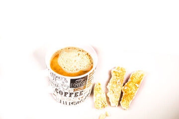 A mug of foamy freshly brewed organic coffee and Italian Biscotti pastries isolated against a white background 