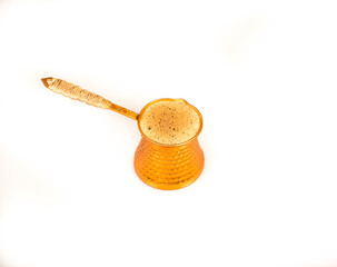 Turkish coffee pot (cezve) with foamy freshly brewed organic coffee isolated against a white background
