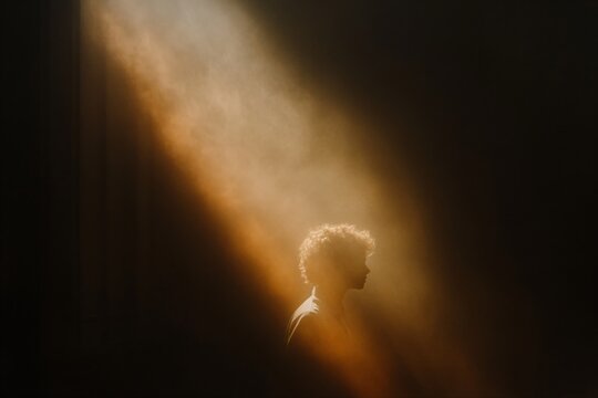 Silhouette of man in divine light beam. Spiritual enlightenment concept. Inspirational image for Easter, Pentecost, Epiphany, Transfiguration. Religious awakening illustration.