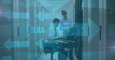 Image of blue arrows over man and woman checking computer servers