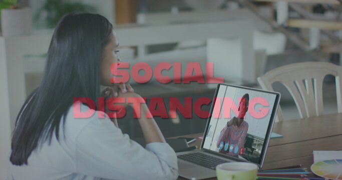 Image of social distancing text over woman using laptop on image call - Powered by Adobe