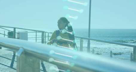 Image of dna strand spinning over woman walking with electric scooter by seaside