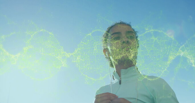 Image of dna strand spinning over woman putting earphones on during exercise - Powered by Adobe