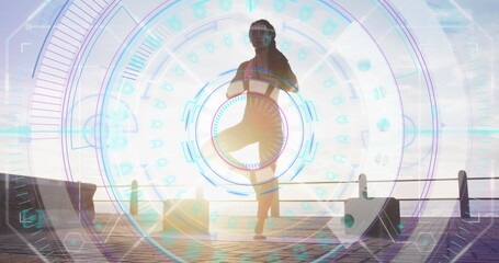 Image of statistics and graphs over woman practising yoga on promenade by the sea