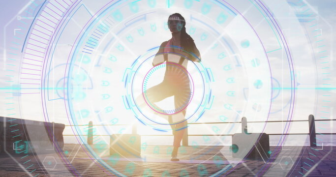 Image of statistics and graphs over woman practising yoga on promenade by the sea - Powered by Adobe