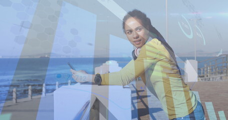 Image of statistics and graphs over woman using smartphone on promenade by the sea