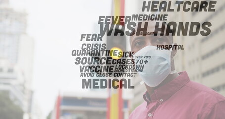 Covid-19 text concept against african american senior man wearing face mask standing on the street