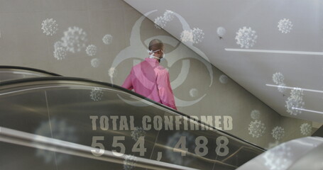 Biohazard symbol with increasing cases against african american senior manusing escalator