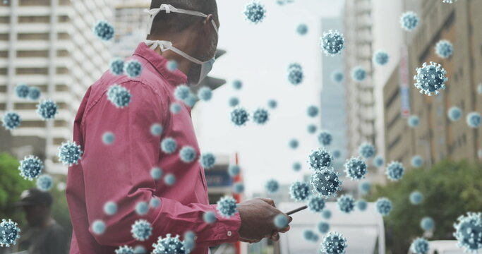 Multiple covid 19 cells floating against man wearing face mask using smartphone on the street