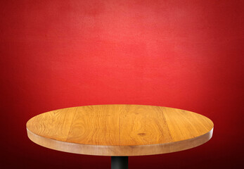 Empty round wooden table on red wall background.