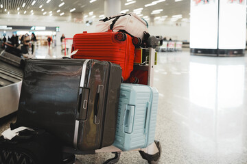 Fototapeta premium Colorful Luggage Stacked on Trolley at Busy Airport Terminal
