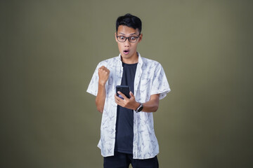 Young Asian man with casual glasses surprised expression getting surprise while pointing to...