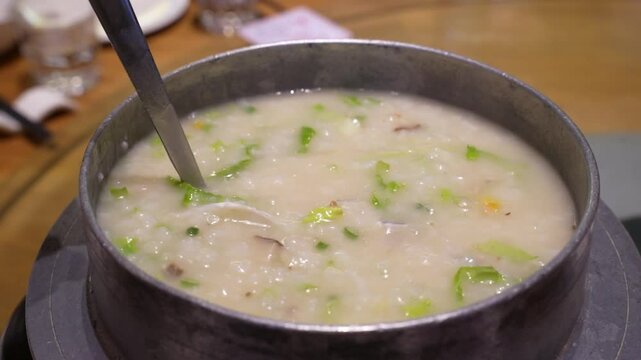 close up of a spoon stirring and scooping rice and fish meat porridge or  congee