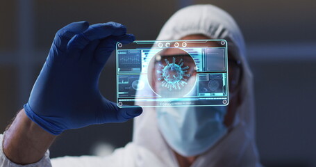 Image of male scientist holding digital screen with covid 19 cell