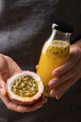 Hand holding fresh passion fruit and bottle of passion fruit juice, Healthy eating