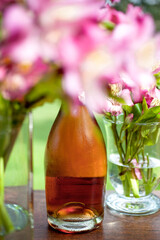 Refreshing cold rose wine bottle resting on table with flowers