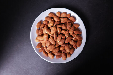 A plate of almonds is on a black table