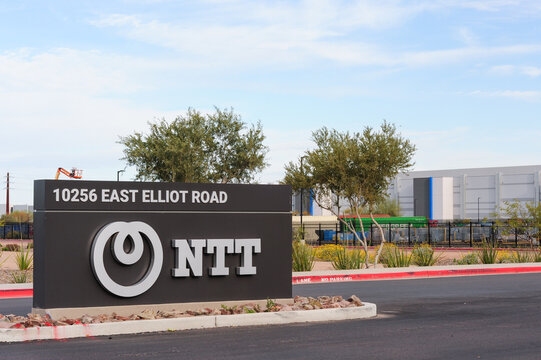 NTT sign marks the entrance to a technology facility near a modern industrial building on East Elliot Road, part of a growing data center corridor in Mesa, Arizona