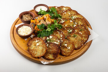Traditional Belarusian or Ukrainian dumplings with fried meat, sautéed vegetables, sour cream, cheese, mushroom sauce and herbs on a wooden platter