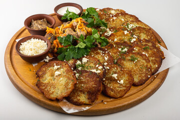 Traditional Belarusian or Ukrainian dumplings with fried meat, sautéed vegetables, sour cream, cheese, mushroom sauce and herbs on a wooden platter