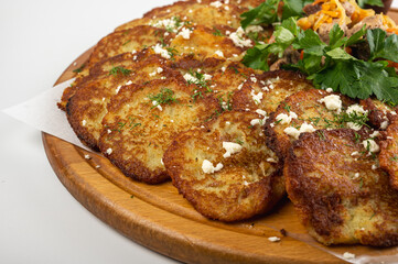 Traditional Belarusian or Ukrainian dumplings with fried meat, sautéed vegetables, sour cream, cheese, mushroom sauce and herbs on a wooden platter