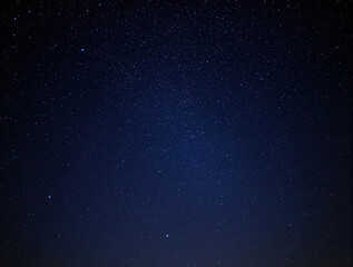 Fototapeta premium Stunning starry night sky with countless twinkling stars scattered across a deep blue gradient, creating a mesmerizing celestial background. Ai generative