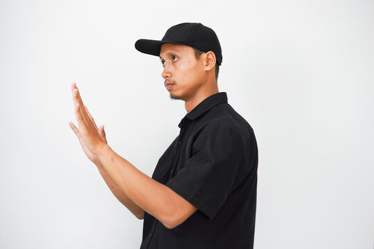 A man in a black shirt and hat is holding his hands up in a gesture of surrender