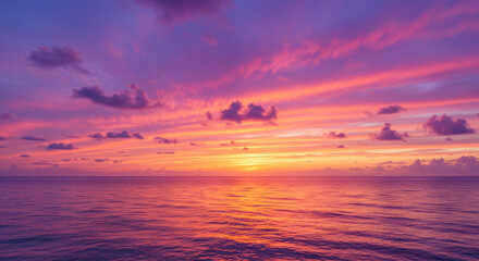 Obraz premium A vivid sunset paints the sky with pink and purple hues over the calm ocean water.