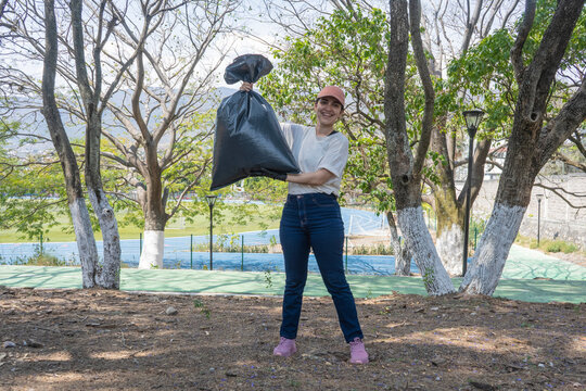 Young female volunteer collecting trash, supporting environmental sustainability through community park cleanup efforts