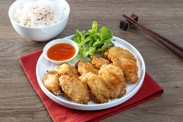 Crispy fried chicken wings served with rice on a wooden table.