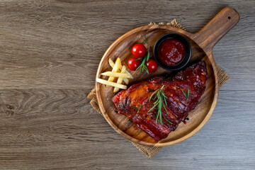 Delicious barbecued ribs seasoned with a spicy basting sauce herbs on wooden chopping board